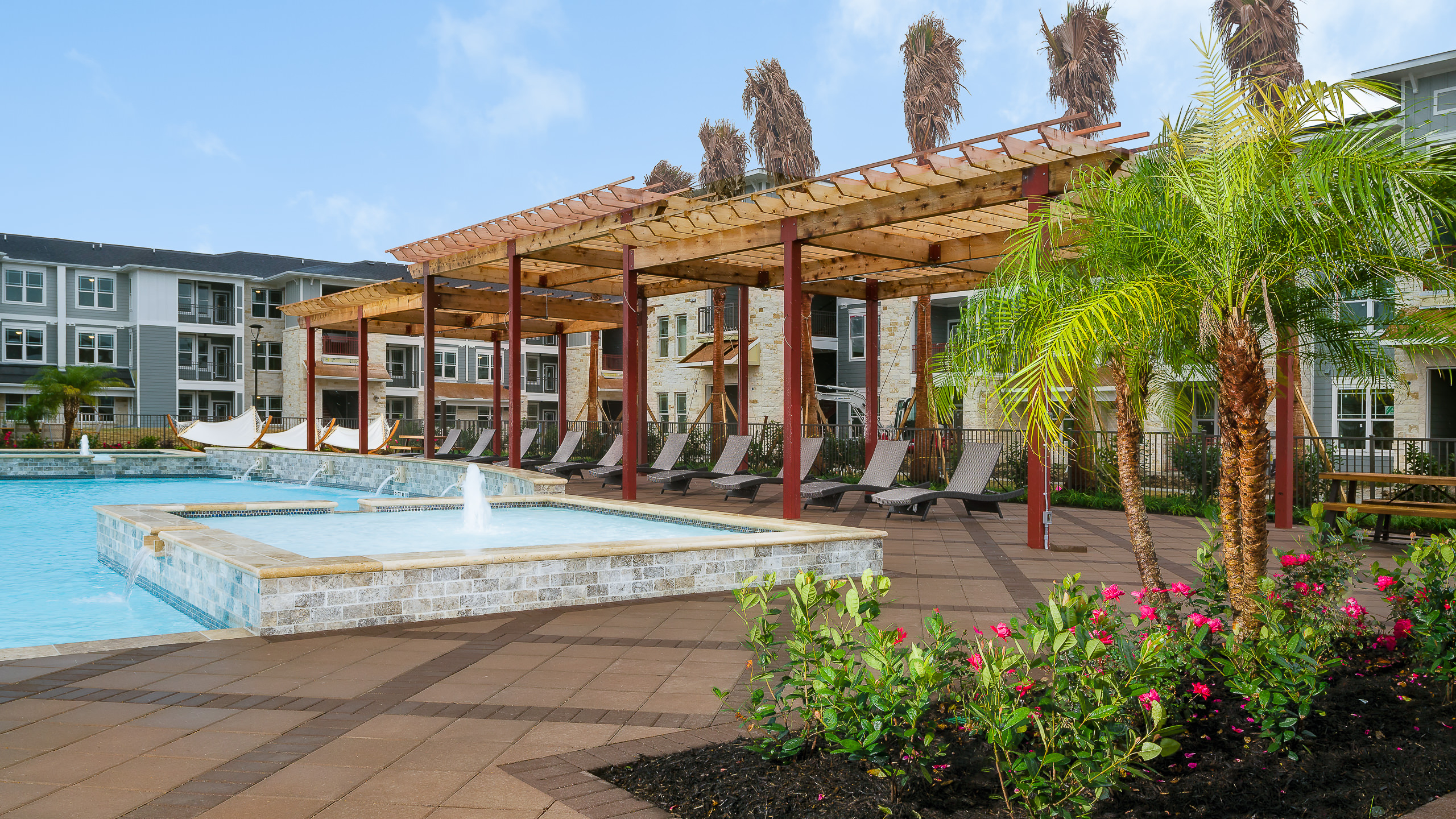 Outdoor architectural photo of an apartment pool area in Baytown, TX, featuring a central water fountain amenity.