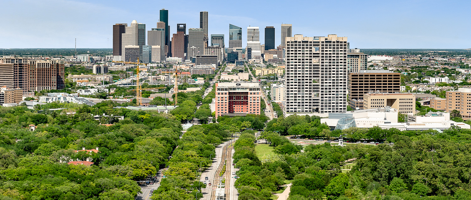 Sunny aerial view looking north over the Texas Medical Center district with the Downtown Houston skyline in the background.