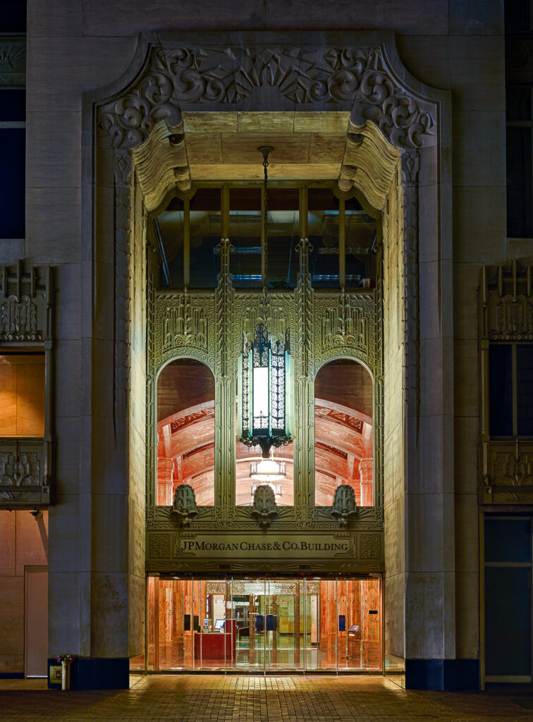 The illuminated art deco facade of the historic Gulf Building, now the JPMorgan Chase building, in downtown Houston at night.