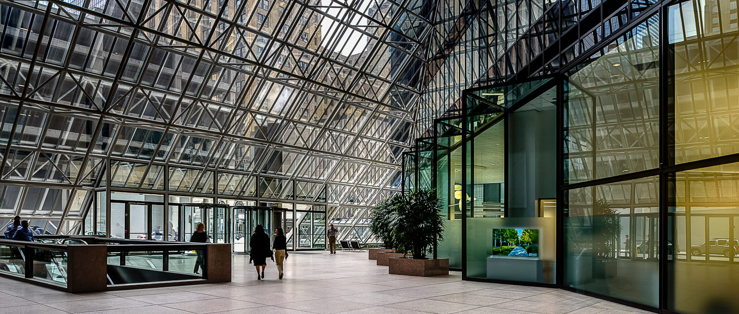 Architectural photo of the large open atrium lobby of Penzoil Place in downtown Houston. An architectural interior photo of the lobby of Pennzoil Place located in downtown Houston, TX. Other buildings can be seen through the atrium of the lobby.