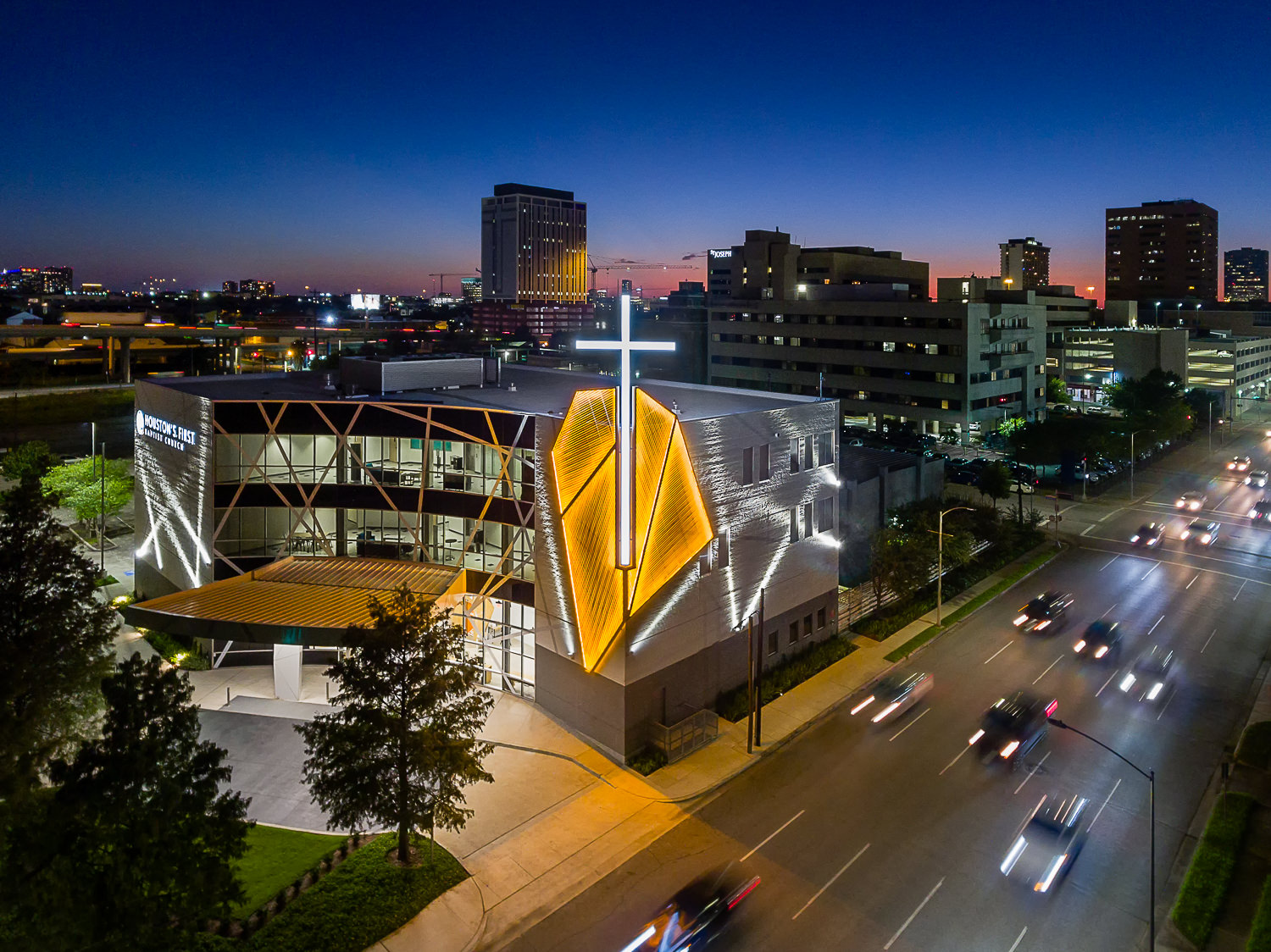 Aerial drone photo of the Houston First Baptist Downtown campus at night, showcasing the unique architectural lighting design.