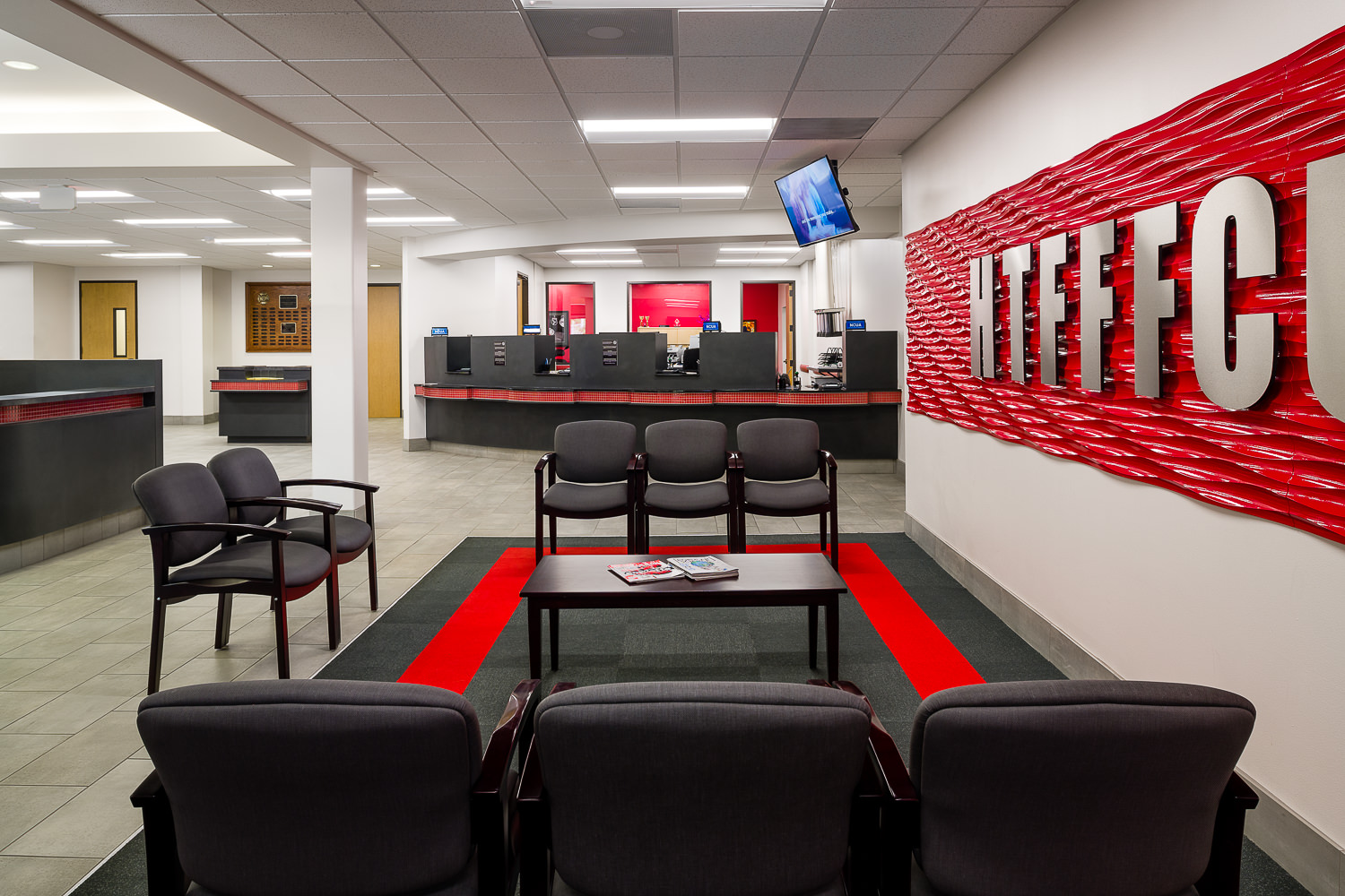 Architectural interior of the renovated Firefighters Credit Union lobby. Bright red accents highlight the modern institutional design.