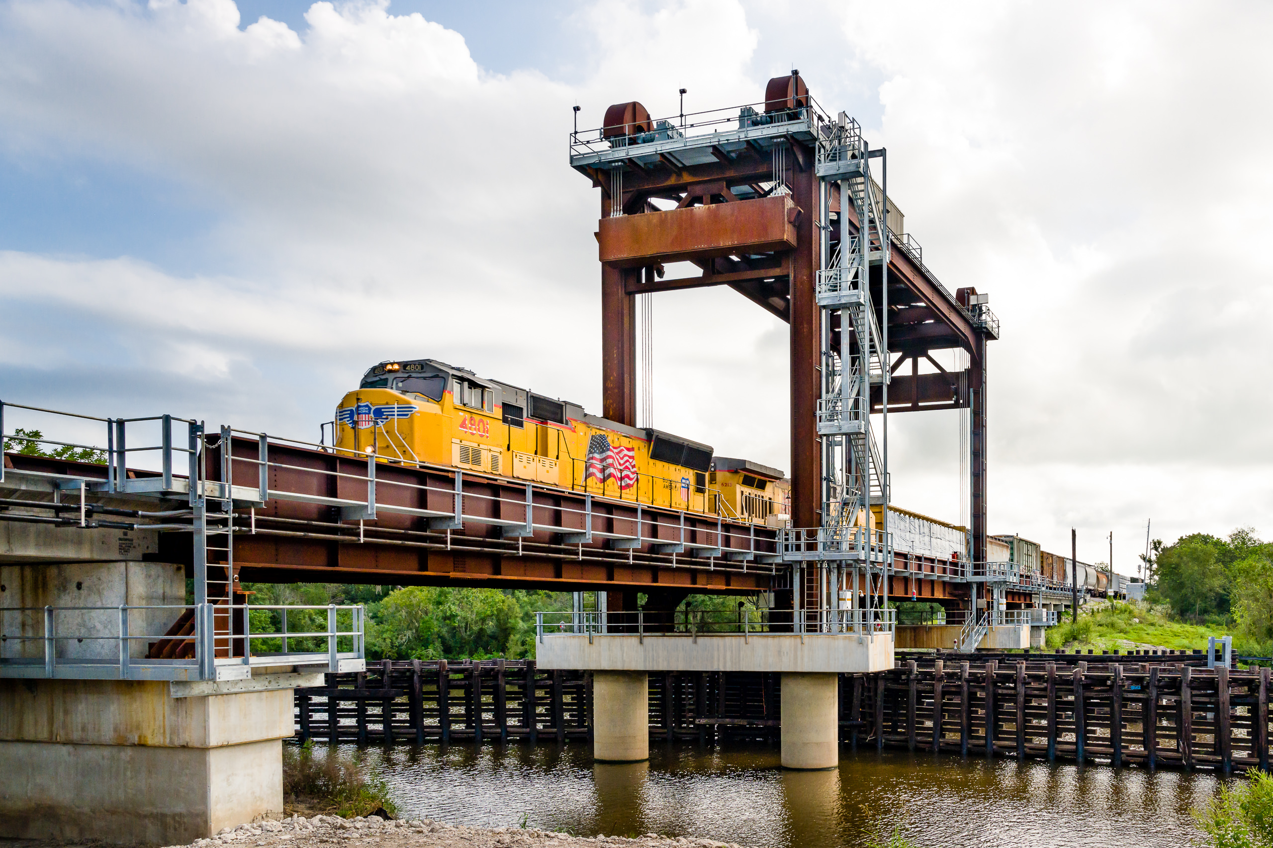 Industrial photo of a train crossing the new vertical-lift bridge, a major infrastructure project on the San Bernard River in Texas.