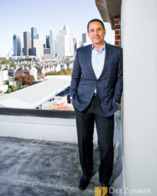 CEO leaning on a wall on the roof with the city of Houston in the background. 
