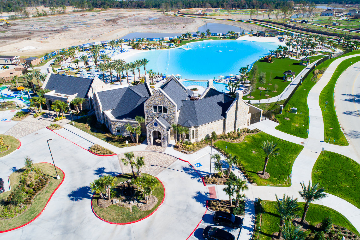 Aerial drone view of a community center and large lagoon amenity in a Northwest Houston real estate development.
