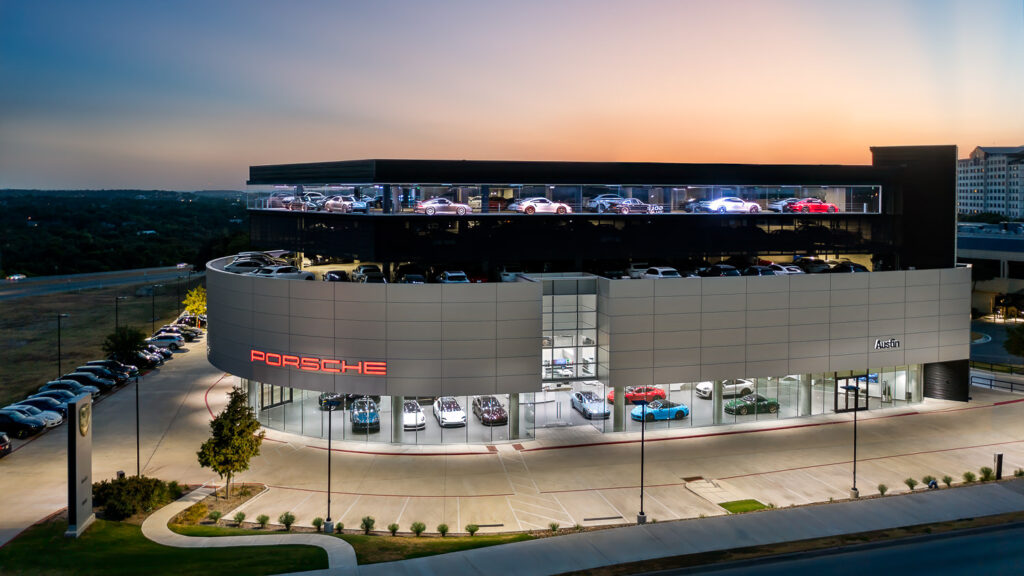 Porsche dealership showroom aerial drone twilight photography Austin Texas luxury automotive commercial exterior hero