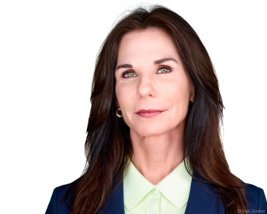 Professional woman headshot, dark hair, green eyes, navy blazer, light green blouse, confident subtle smile, studio white backdrop, Houston TX.