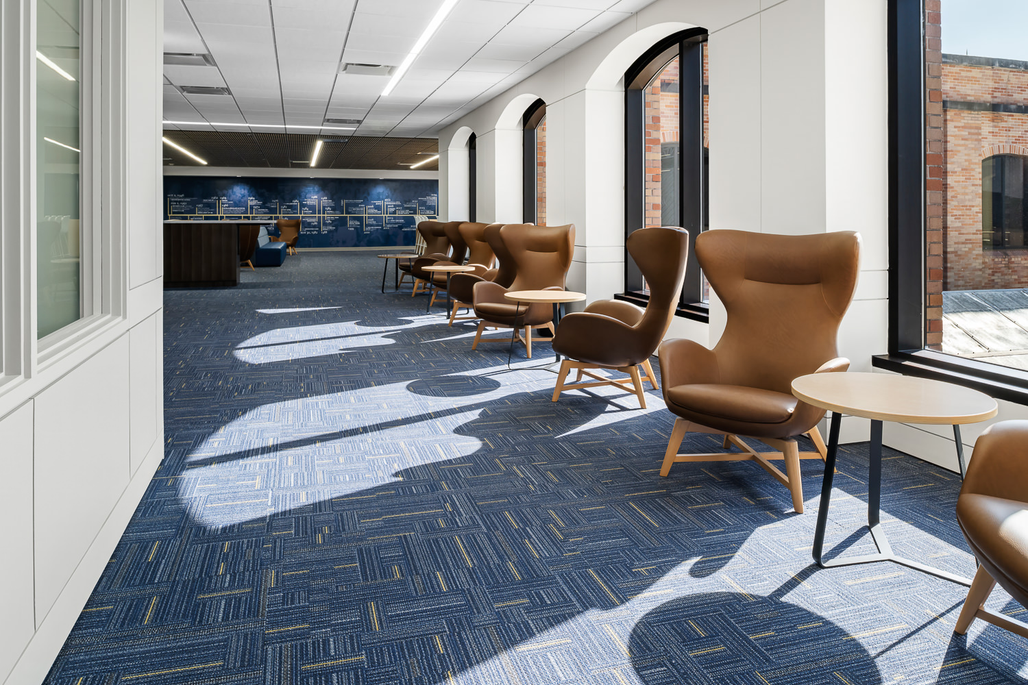 Interiors photo of the Second Baptist School library lounge. Natural sun streams in, illuminating the bright institutional community space.