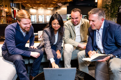 lifestyle branding image of 4 cowrokers huddled around a computer reviewing a presentation