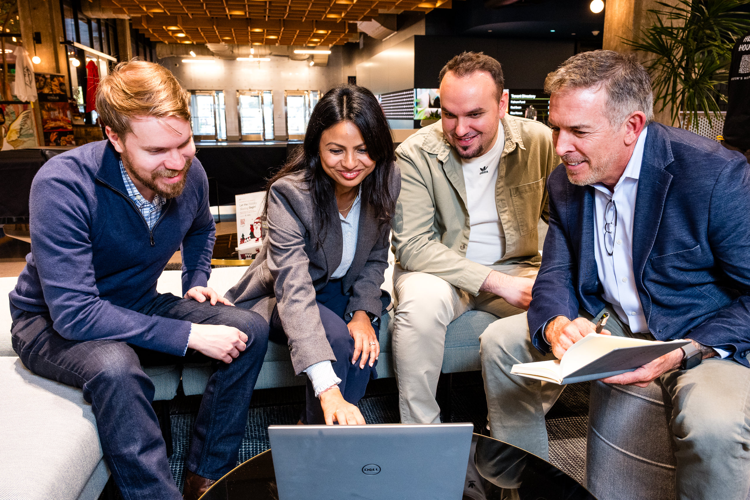 lifestyle branding image of 4 cowrokers huddled around a computer reviewing a presentation