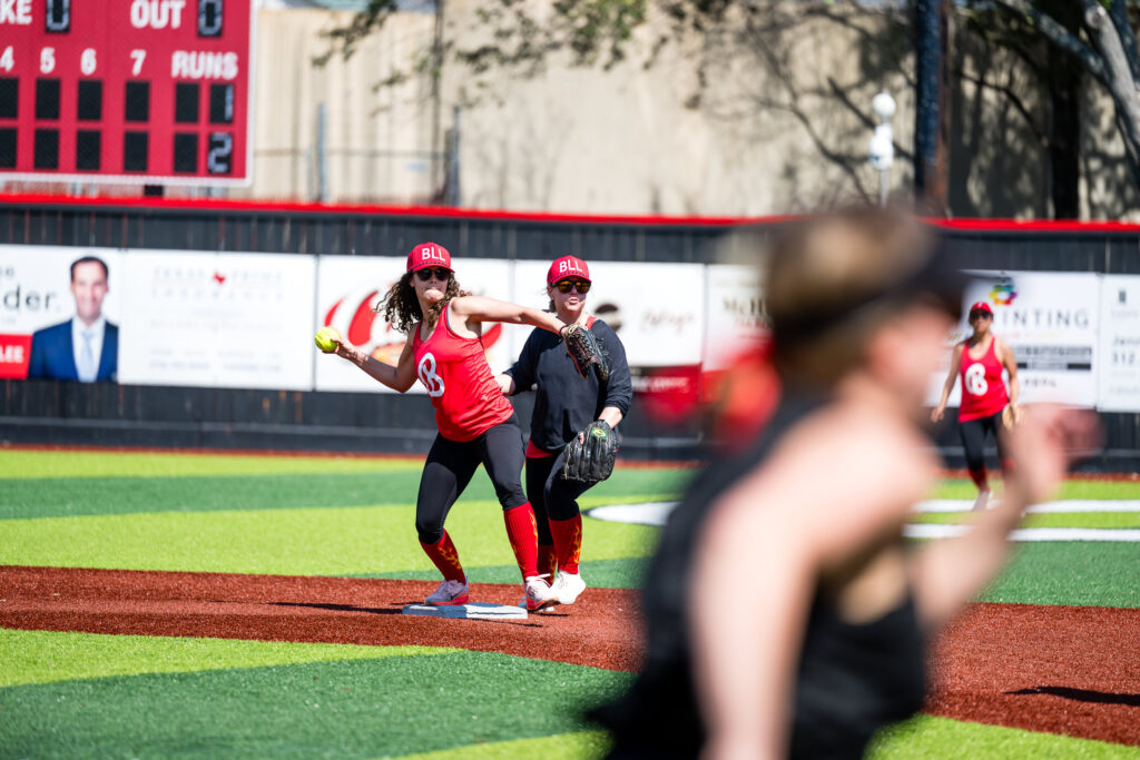 Red Team player making a throw to first base during mom's softball game on Bellaire Little League Opening day 2026
