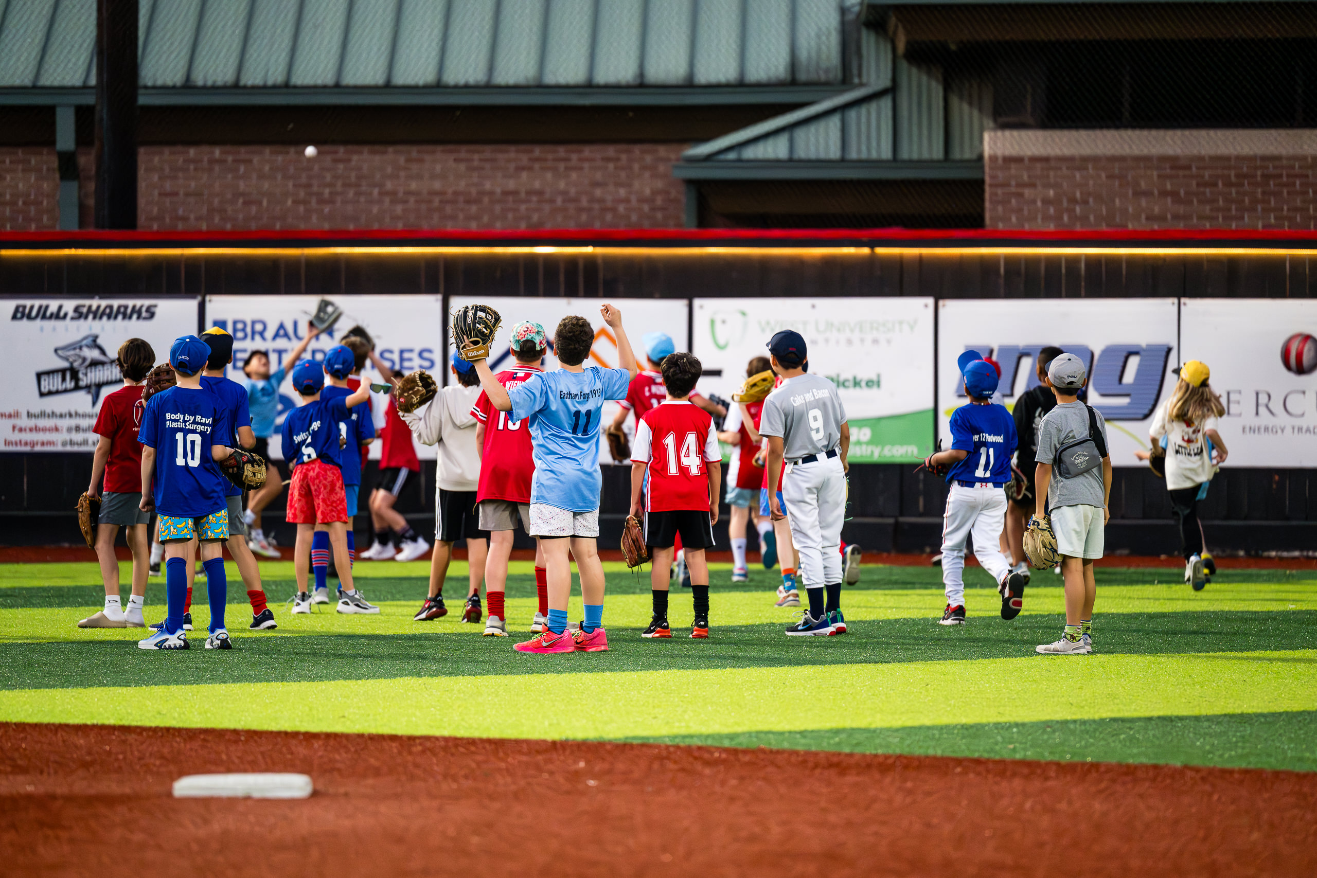 Players watch as a ball goes over the left field fence at Weston Field on the Bellaire Little League Opening Day during the Home Run Derby
