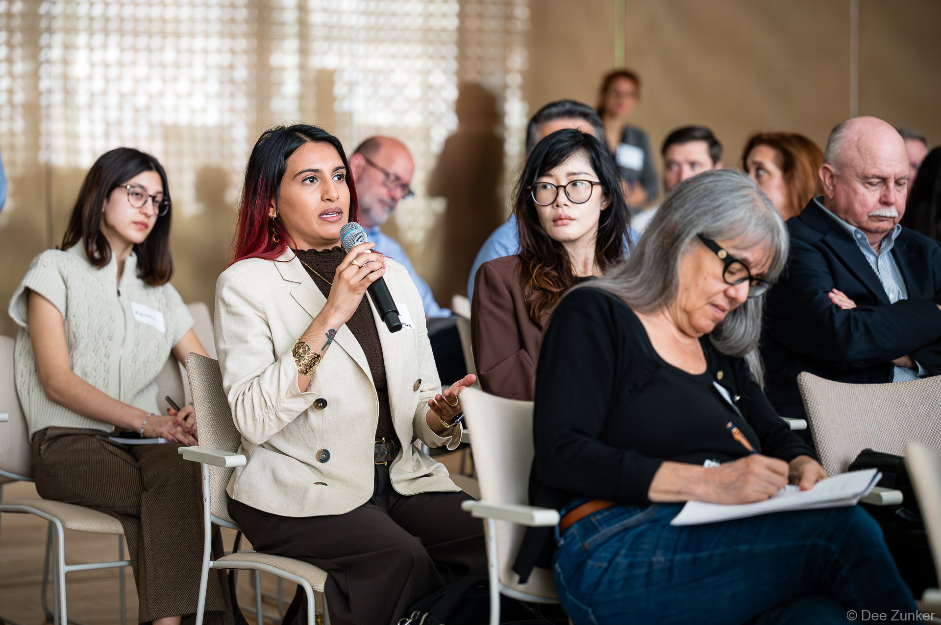 Attendee asks a question via microphone during Gulf Coast Green 2026 at The Ismaili Center, Houston, as audience members listen and take notes.