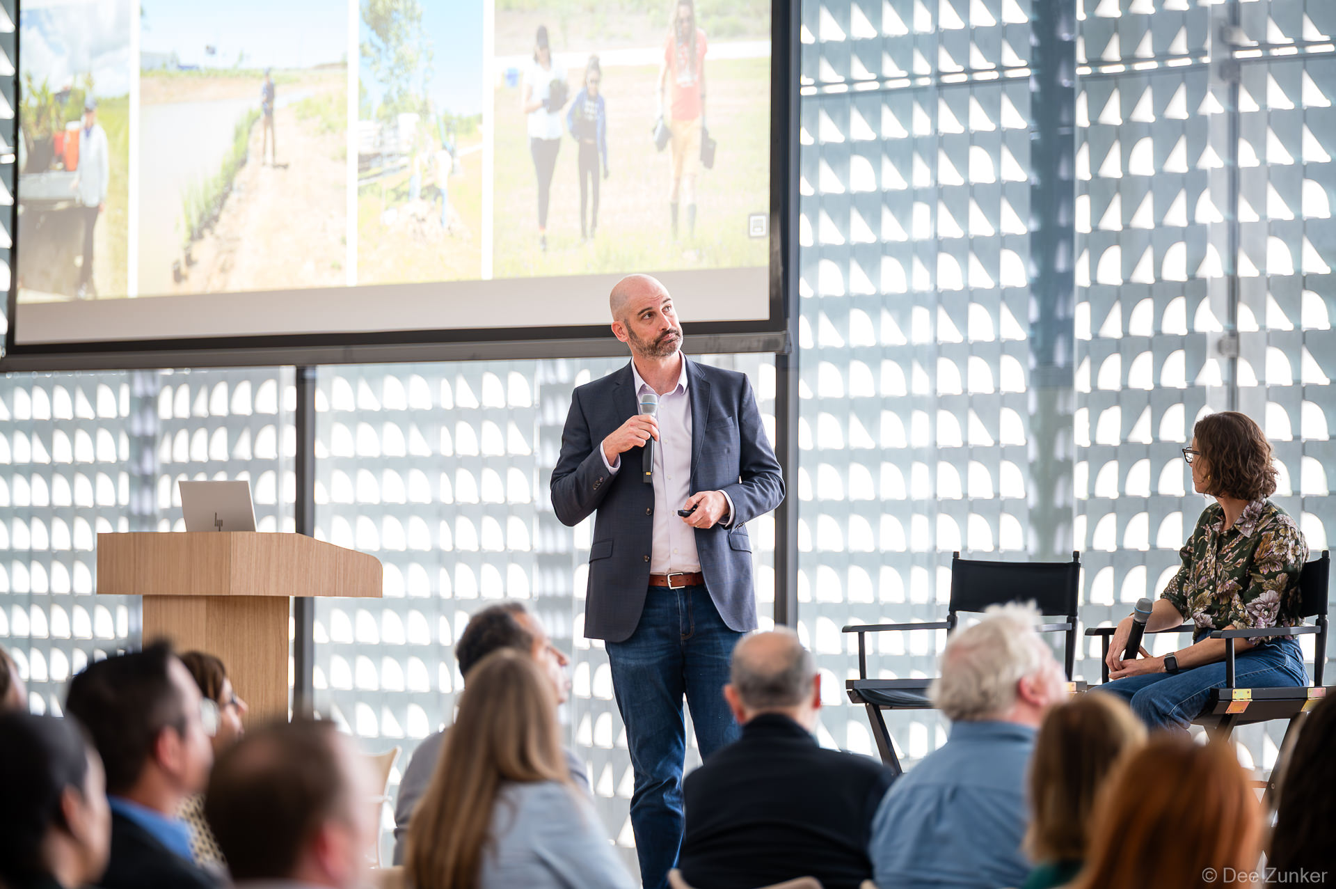 Blake Coleman holds microphone and presents to seated audience at Gulf Coast Green 2026 conference inside The Ismaili Center, Houston.