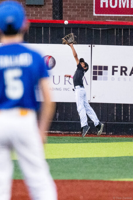 Mariners outfielder leaps at the warning track to catch a fly ball at Bellaire Little League American League game, Bellaire TX.