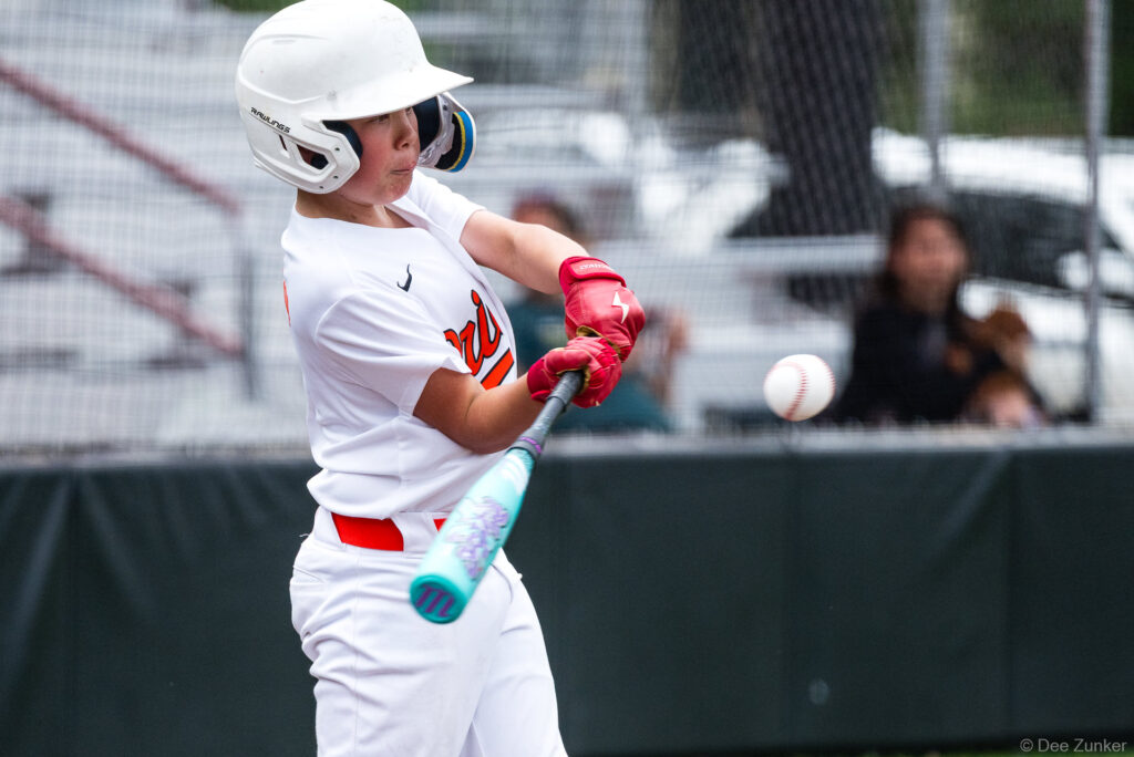 Rays batter in white uniform swings at an incoming pitch during a Bellaire Little League American League game at Weston Field, Bellaire TX.