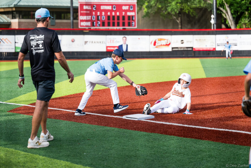 Orioles baserunner slides into third base as Rays fielder attempts tag at Bellaire Little League American League game at Weston Field.