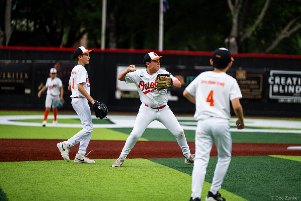 Bellaire Little League Orioles player throws ball to teammate during American League game at Weston Field in Bellaire TX.