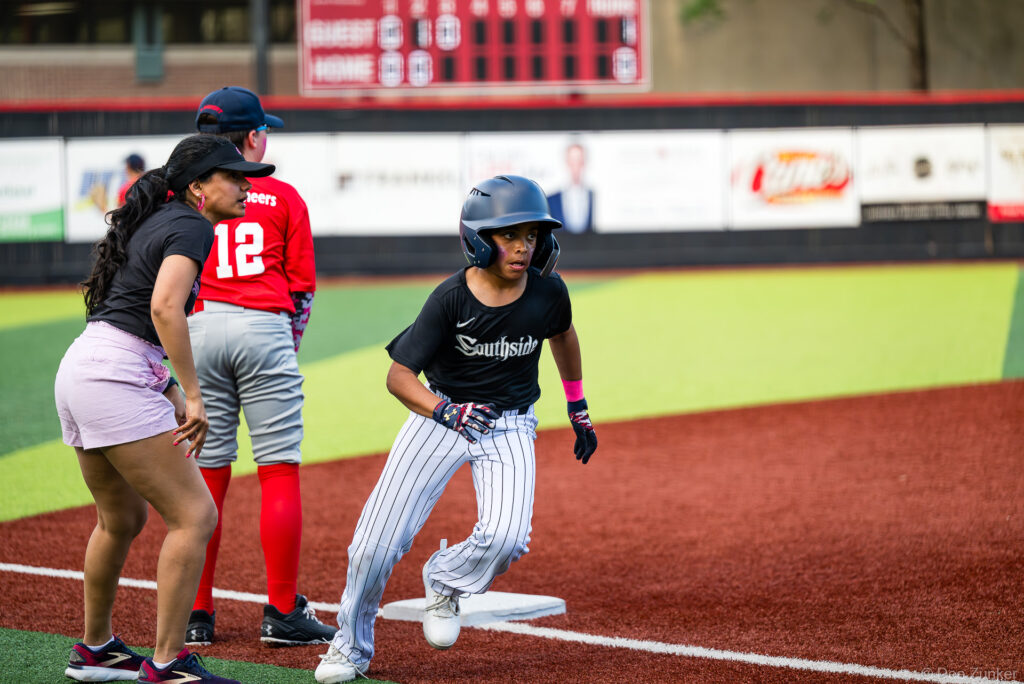 Bellaire Little League White Sox baserunner rounds third base at Weston Field during an American League game against the Red Sox.