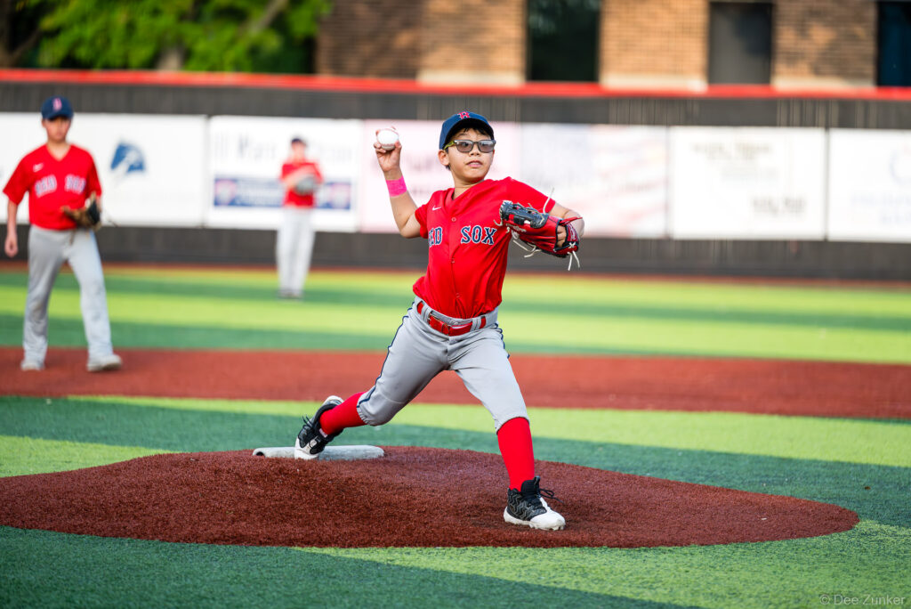 Young Red Sox pitcher winds up on the mound during a Bellaire Little League American League game at Weston or Tiras Field in Bellaire TX.