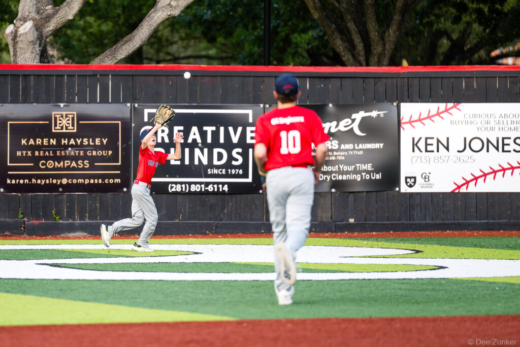Red Sox outfielder catches a fly ball near the warning track at Bellaire Little League American League game, Bellaire TX.