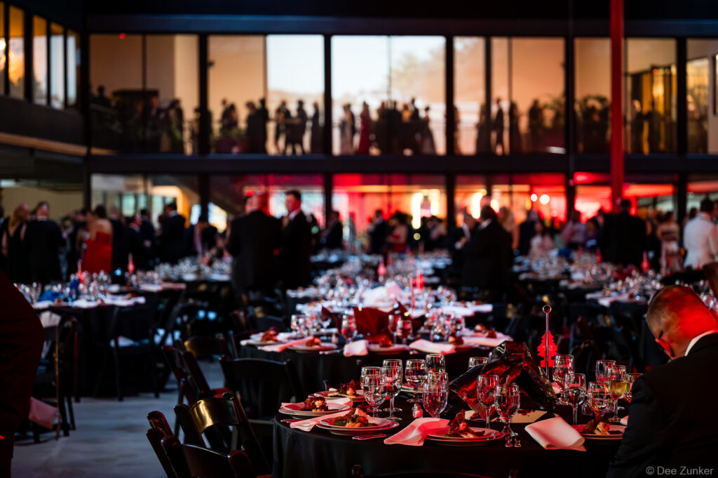 Elegant gala dinner tables set with glassware and red decor inside The Shop Club Houston during the 40th Annual AIA Houston Design Gala.