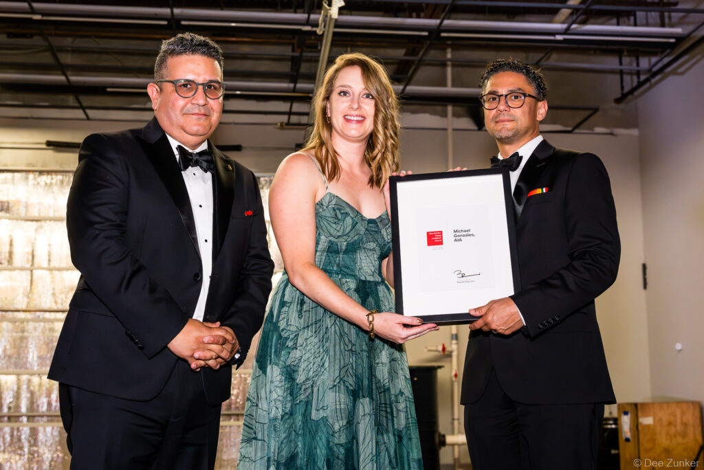Three formally dressed attendees present a framed AIA award certificate to Michael Gonzales AIA at The Shop Club Houston Design Gala.