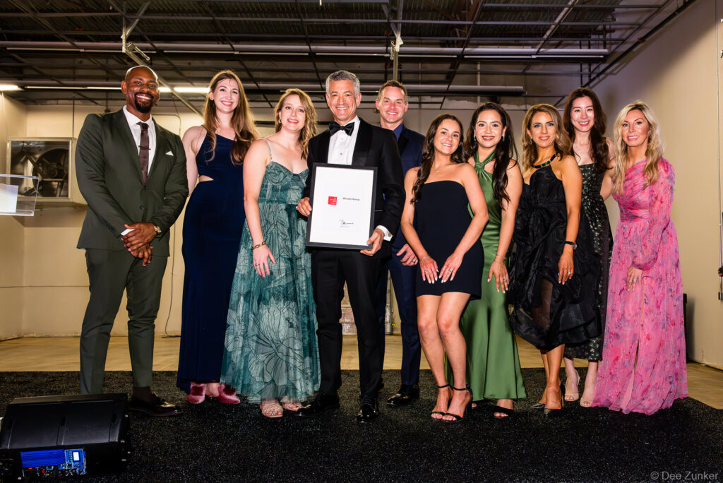 Group of ten professionals in formal attire accepting a framed award on stage at the 40th Annual AIA Houston Design Gala at The Shop Club Houston.