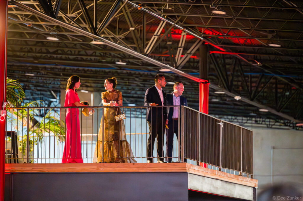 Four formally dressed guests mingle on the mezzanine balcony at The Shop Club Houston during the 40th Annual AIA Houston Design Gala.