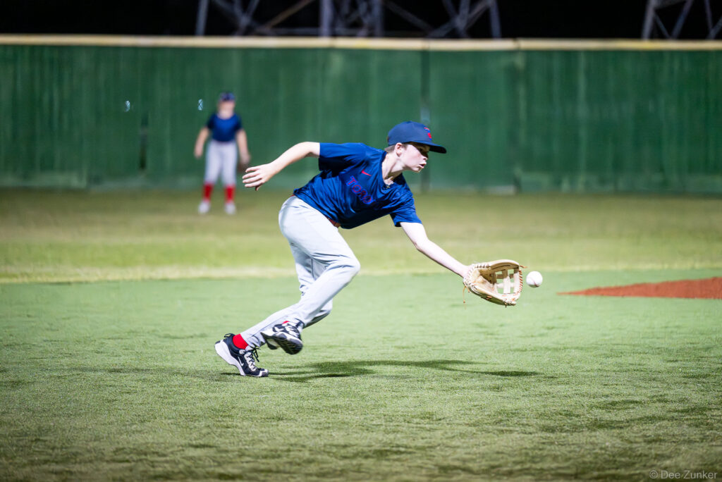 Young Blue Jays infielder stretches to field a ground ball during a Bellaire Little League American League game at Weston or Tiras Field in Bellaire TX.