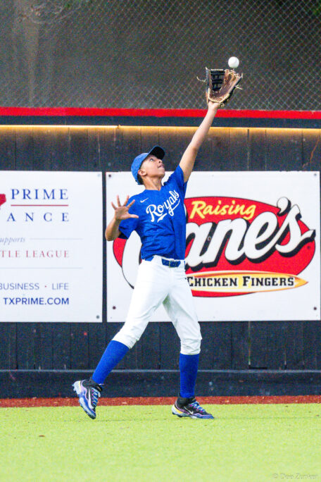 Bellaire Little League Royals outfielder leaps to catch a fly ball at Weston Field during an American League game against the Yankees.