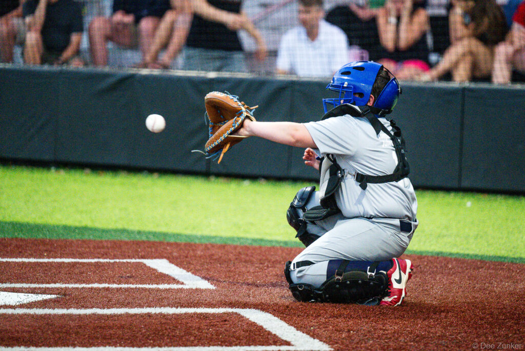 Royals catcher in blue helmet reaches to catch a pitch at Bellaire Little League American League game, Weston Field, Bellaire TX.