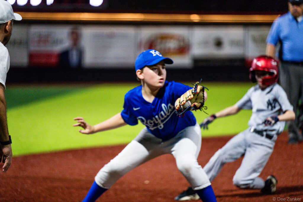 Bellaire Little League Royals infielder catches throw at base as Yankees runner slides in during American League game at Weston Field.