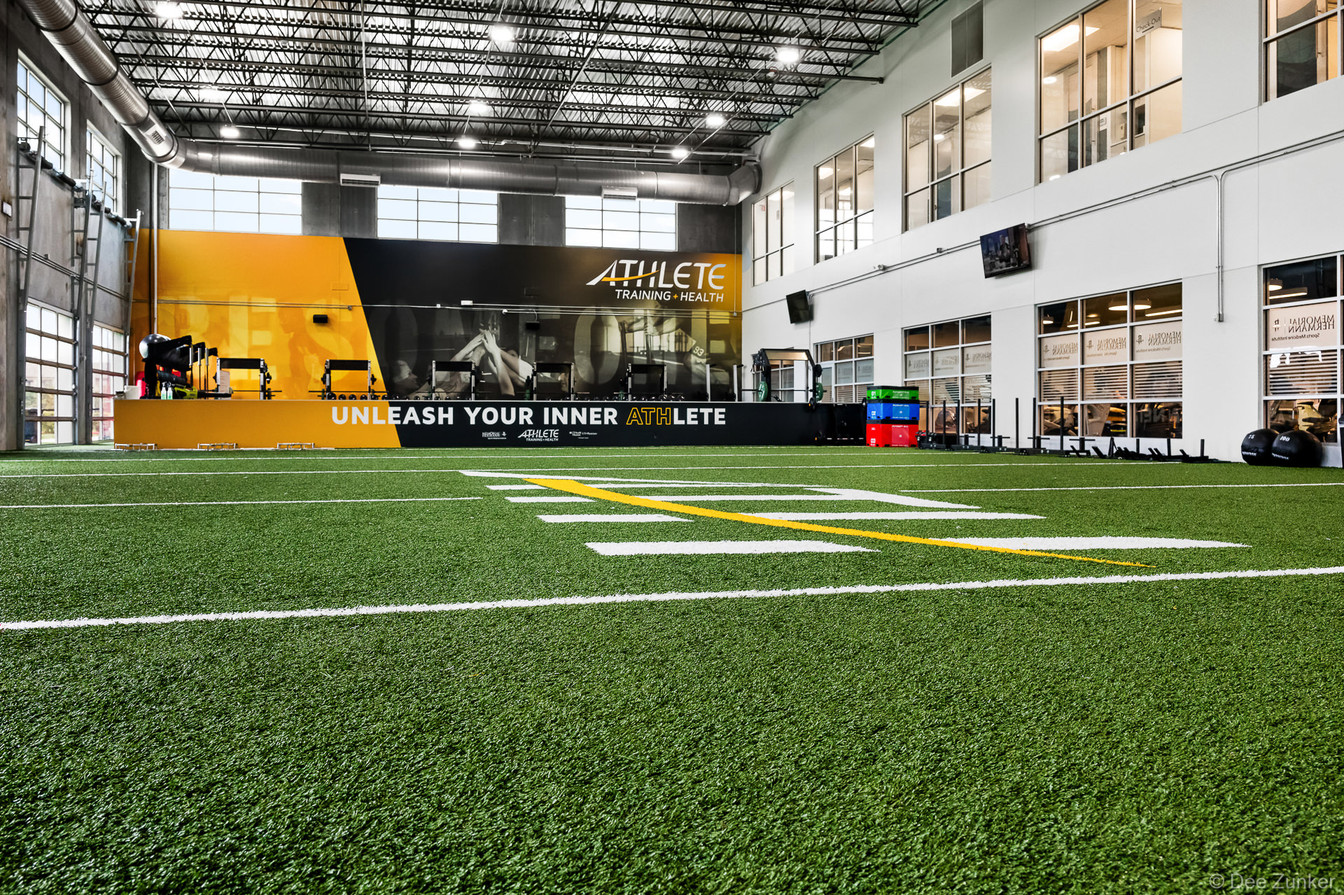 Indoor turf training facility at Athlete Training and Health in Pearland TX featuring yard lines and branded motivational wall signage.