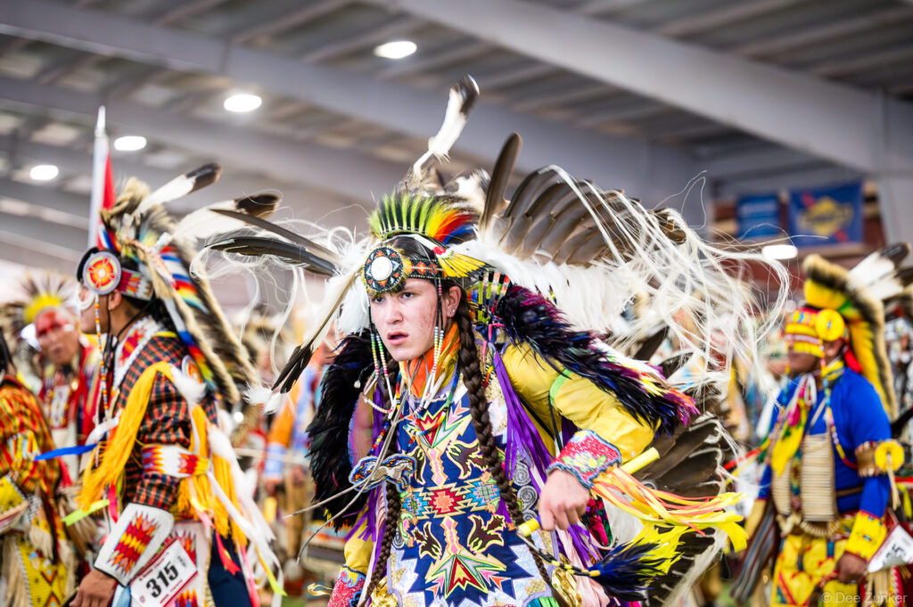 Native American dancer in full regalia with feathered headdress performing at Alabama-Coushatta 56th Annual Powwow Grand Entry, Texas