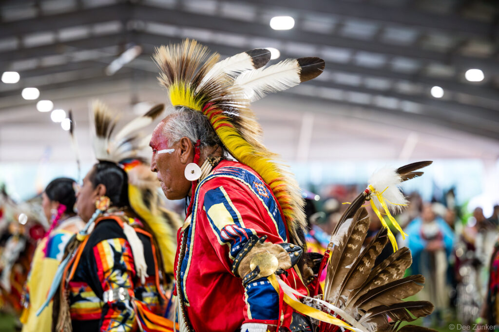 Native American elder in traditional regalia with feathered headdress and face paint during Grand Entry at Alabama-Coushatta 56th Annual Powwow Texas