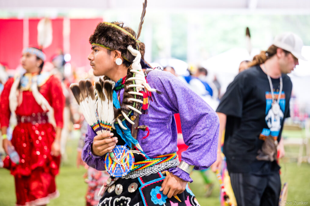 Native American dancer in purple regalia holding feather fan at Alabama-Coushatta 56th Annual Powwow, Livingston, Texas