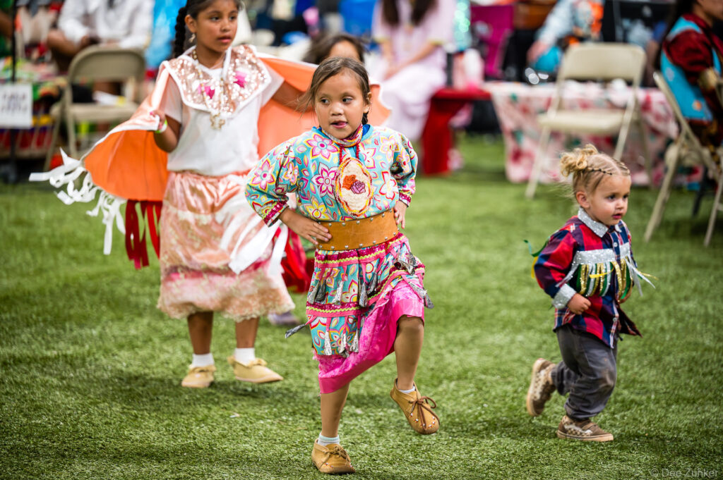 Three young girls in traditional regalia dance at the Alabama-Coushatta 56th Annual Powwow in Texas, June 2026.