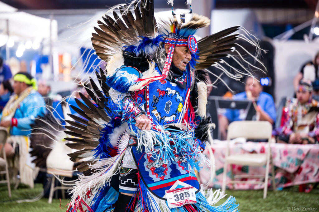 Elder male dancer in elaborate blue regalia with eagle feather bustle performs at Alabama-Coushatta 56th Annual Powwow Texas