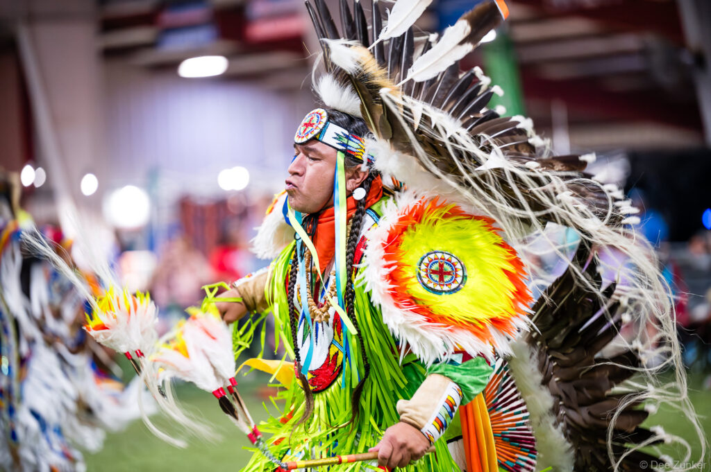 Native American male dancer in vibrant regalia with feathered bustle and headdress performing at Alabama-Coushatta 56th Annual Powwow Texas
