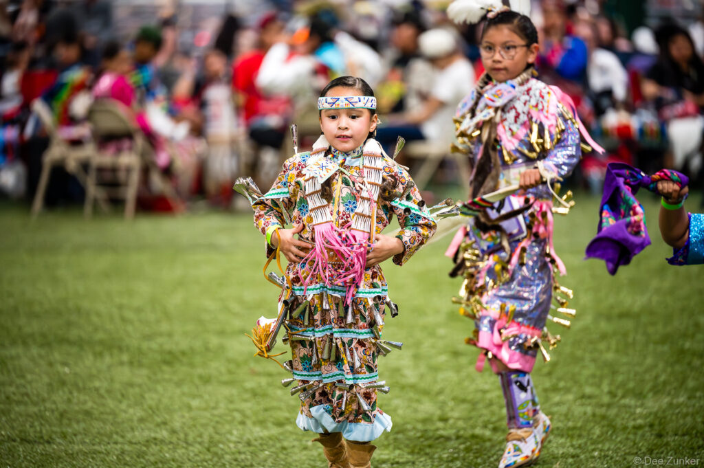 Two young Native American girls in colorful jingle dress regalia dancing at the Alabama-Coushatta 56th Annual Powwow in Texas