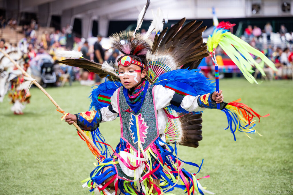 Young Native American boy dancer in colorful regalia with feather bustle and face paint performs at Alabama-Coushatta 56th Annual Powwow Texas