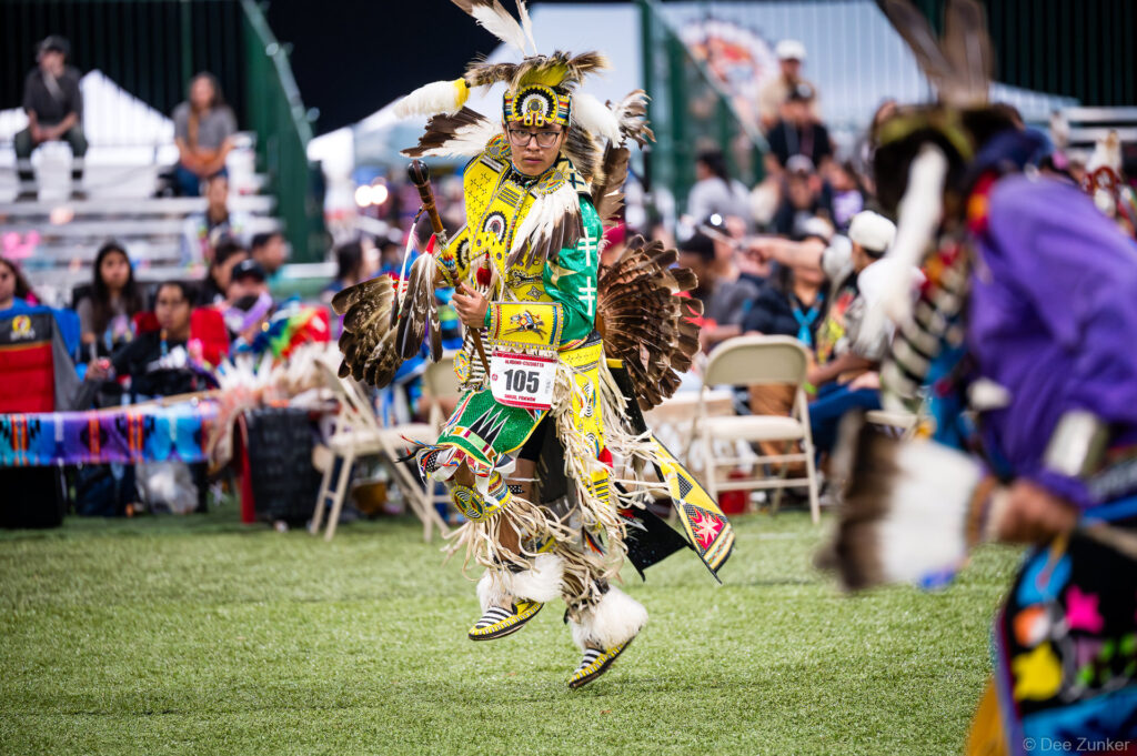 Male dancer number 105 in yellow feathered regalia performs at the Alabama-Coushatta 56th Annual Powwow in Texas