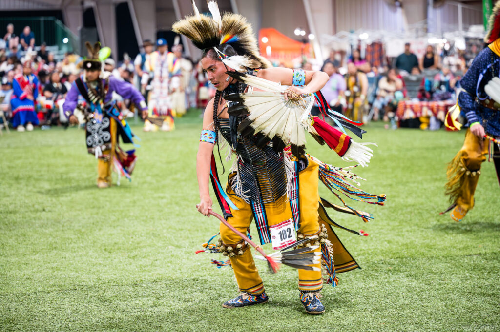 Native American dancer in traditional regalia performs at the Alabama-Coushatta 56th Annual Powwow in Texas, competitor number 102.