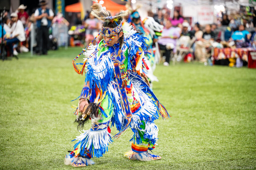 Native American dancer in vibrant blue fringed regalia performing at the Alabama-Coushatta 56th Annual Powwow in Texas