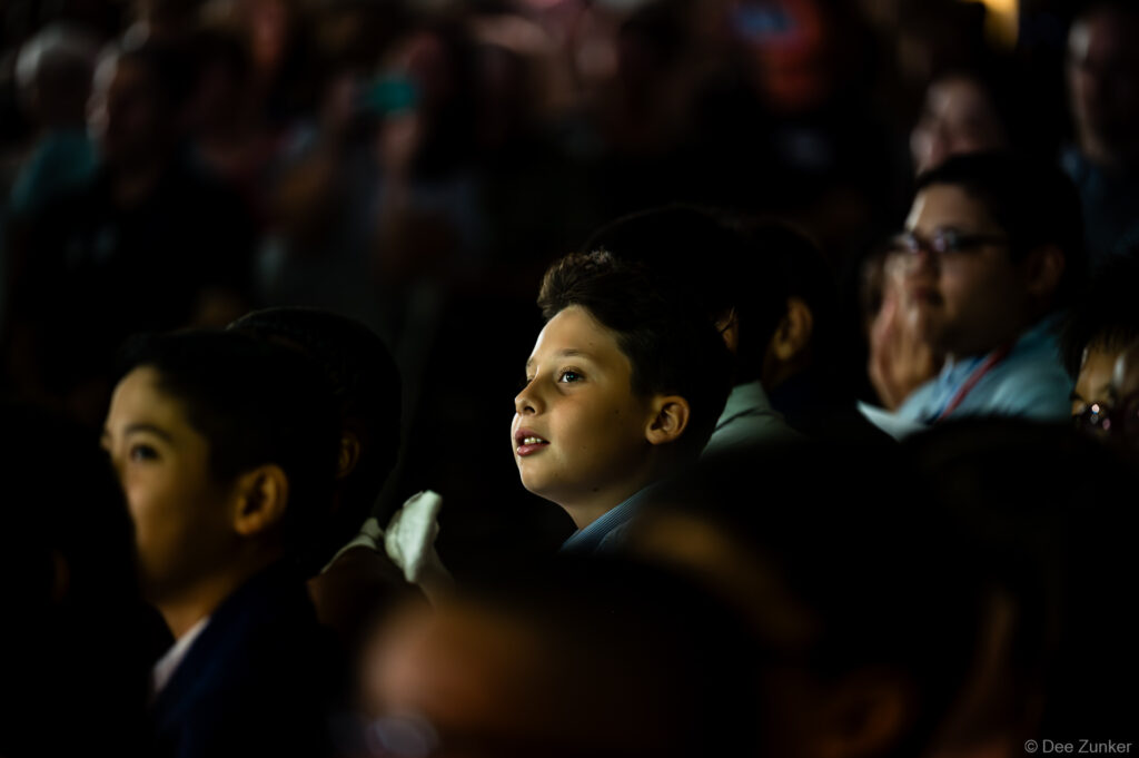 Young boy in crowd watches Horn Elementary 5th grade graduation ceremony with wonder, Bellaire TX, photographed by Dee Zunker