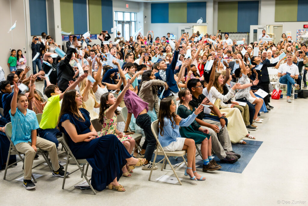 Students and families toss face masks in celebration at Horn Elementary 5th grade graduation ceremony in Bellaire TX