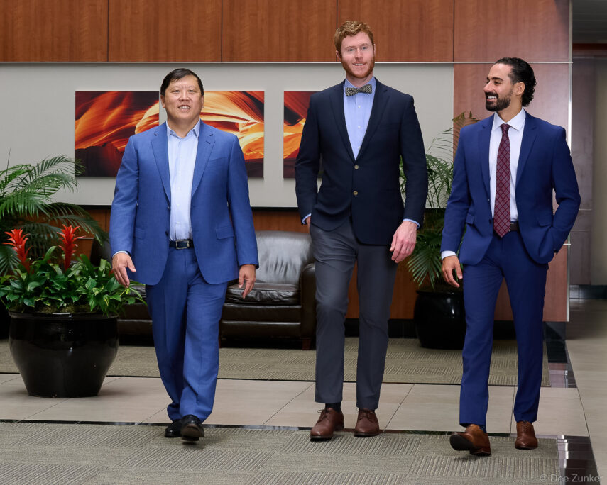 Three businessmen in suits walking through a modern corporate office lobby in Houston, captured for professional branding photography.