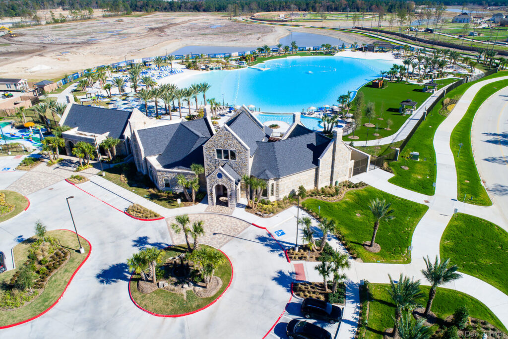 Aerial drone view of a community center and large lagoon amenity in a Northwest Houston real estate development.