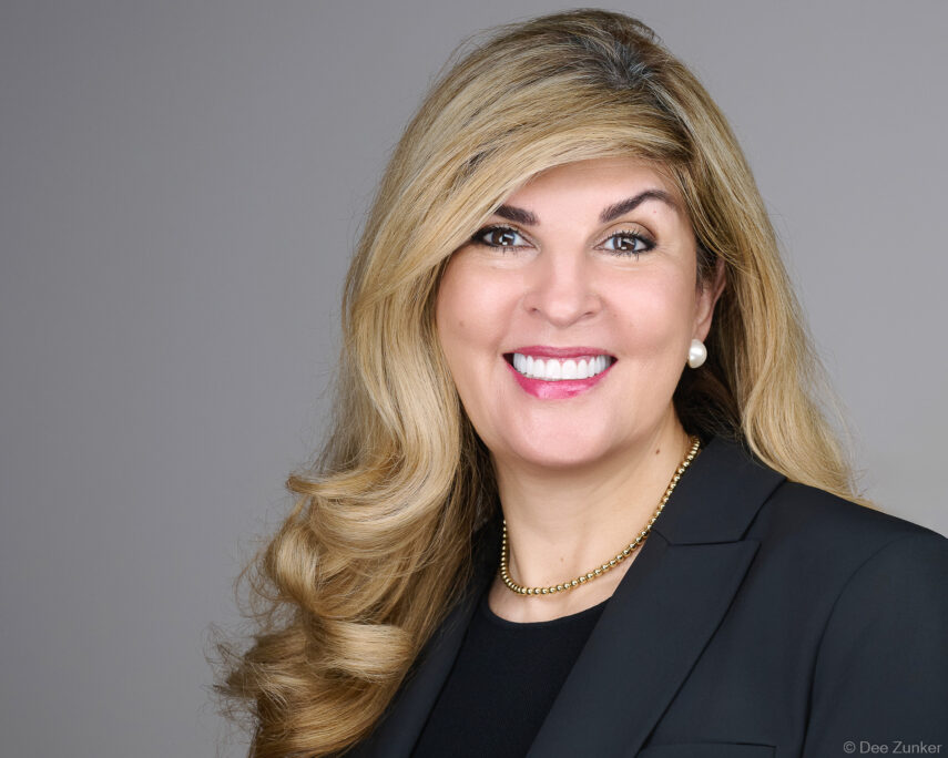 Professional corporate headshot of a female attorney on a gray studio background, photographed for a Bellaire Houston law firm.